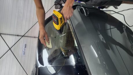 Een specialist van Protect Car Care brengt nauwkeurig raamfolie aan op een autoruit
